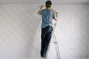man removing tape from wall after paint job