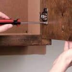 image of person taking off hinges from cabinet