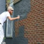 image of man spray painting brick
